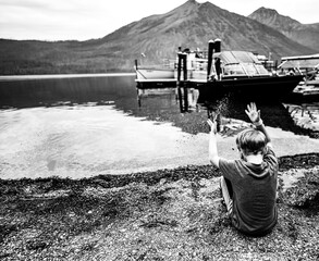 Young boy tossing sand into Lake McDonald at Glacier National Park