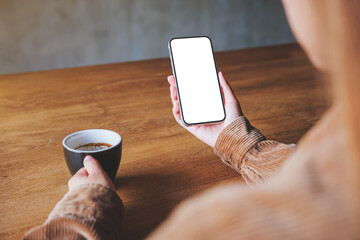 Mockup image of hands holding mobile phone with blank desktop screen while drinking coffee