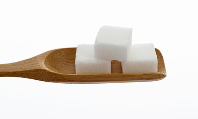 Sugar cubes in wooden scoop on white background