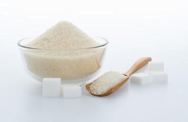 Fototapeta na wymiar A bowl granulated sugar and sugar cubes on white background