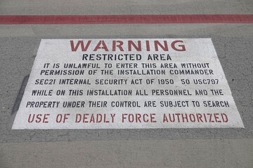 Warning - Restricted Area - Use of Deadly Force Authorized Sign on Pavement at a military base in the USA