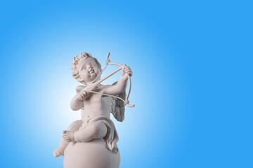 Figurine of an angel Cupid on the podium with a bow and arrow on a blu background . Valentine's Day.Place for text. - obrazy, fototapety, plakaty