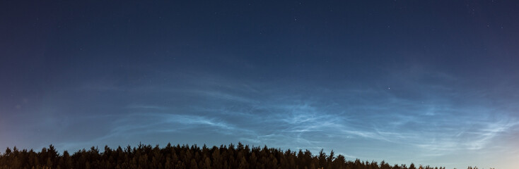 Fototapeta na wymiar Noctilucent clouds, night shining clouds, are tenuous cloud-like phenomena in upper atmosphere of Earth, visible in northern hemisphere, most often in June July / summer nights. wide panoramic shot