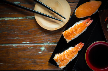 Sushi Set nigiri shrimp and salmon and sushi california rolls with avocado and maki with carrot, on wood,top view