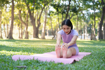 Naklejka na ściany i meble Attractive young Asian woman practice yoga, exercise in the park, standing one leg on a yoga mat, showing balance posture. Wellbeing lifestyle and activity concept
