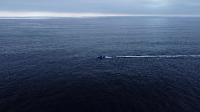 Little skiff out in the ocean with the shore in the background