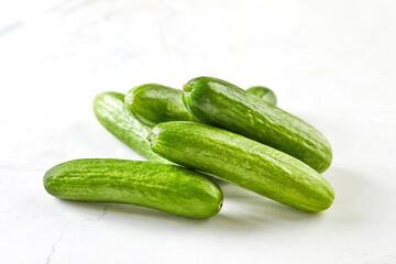 Mini cucumbers on white marble, ready to cook and eat