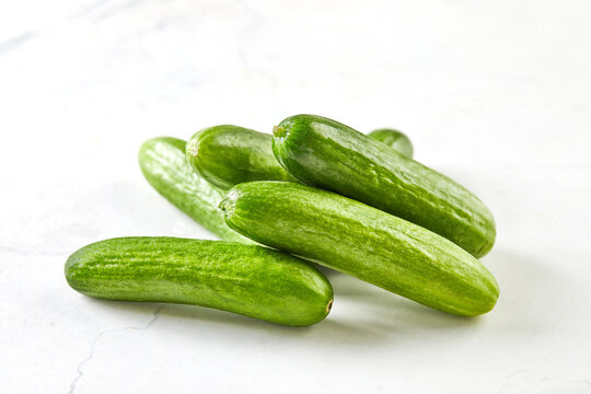 Mini cucumbers on white marble, ready to cook and eat