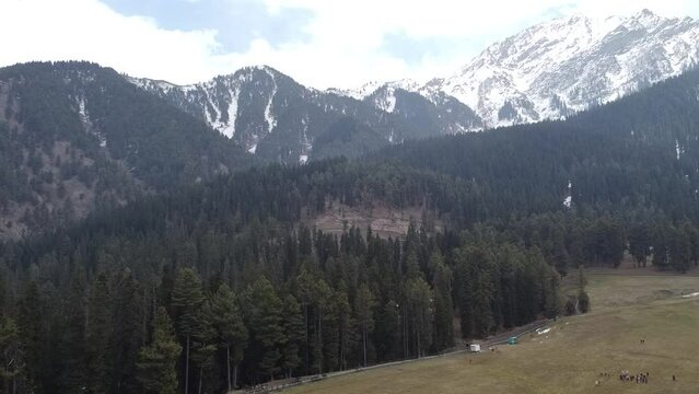 Aerial slow movement around mountain landscape surrounded by dense trees