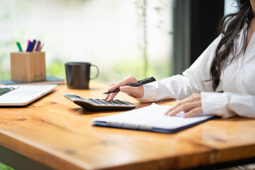 Businesswoman use calculators and a computer with a holding pens on desks in the office. finance and accounting concept