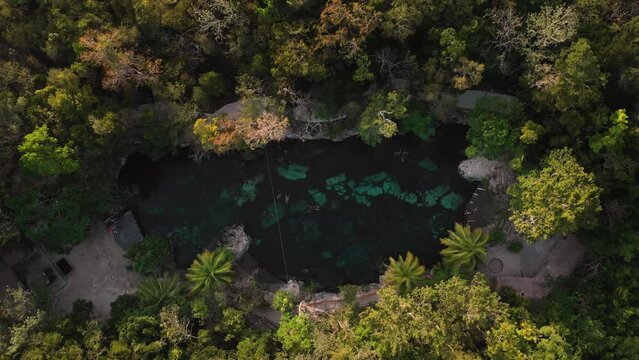 Cinematic aerial top-down shot of drone flying upward of mirrored turquoise Cenote Casa Tortuga, Tulum