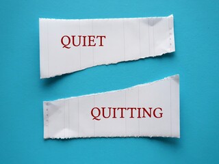 Torn paper on blue background with text written QUIET QUITTING, Trend of employees choosing to not go  beyond their jobs or not subscribing to hustle culture mentally