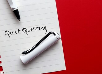 Pen and paper on red background with with handwritten text QUIET QUITTING, buzzword trend of...
