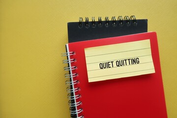Notebook on copy space yellow background with handwritten stick note QUIET QUITTING, buzzword trend...