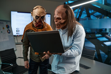 Two zombie businessmen looking at laptop screen