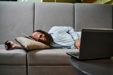 Overworked zombie sleeping on sofa in office - Powered by Adobe
