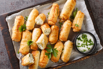 Borek is a Turkish pastry with savory filling with cheese and spinach closeup on the wooden board on the table. Horizontal top view from above