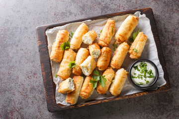 borek sigara boregi fried pastry wrapped in cheese in phyllo closeup on the wooden board on the table. Horizontal top view from above