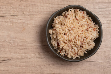 cooked brown rice in a cup on wooden background