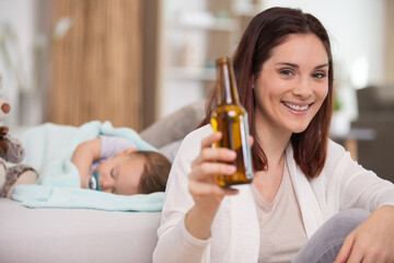 Fototapeta premium happy woman drinking a beer while baby sleeps