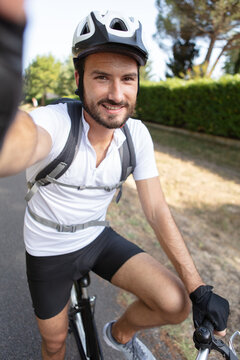 happy smiling cyclist man driving a bike taking selfie photo