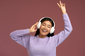 Crazy asian woman in headphones singing rejoicing and showing peace gesture