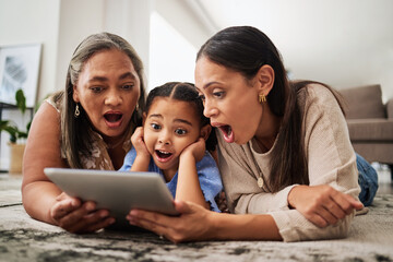 Fototapeta premium Digital tablet, family and wow in a living room with multigenerational women bonding on a floor, surprised, shock and excited. Relax, happy family and good news with mother, girl and grandma online