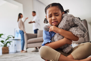 Sad, little girl and crying from parent fight, argument or divorce hugging teddy at home. Unhappy...
