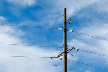 Power lines on the background of the blue sky close-up. Electric hub on a pole. High voltage wires
