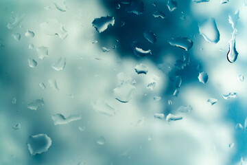 Water drops on glass against blue sky, rainy season concept. Window view background screensaver