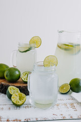 lemonade drink with green lemons or lime on Jar and glass on white background in Latin America	
