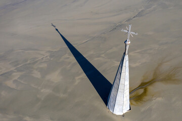 Aerial apocalyptic scene, church tower with cross buried under mud and toxic copper mining residuals