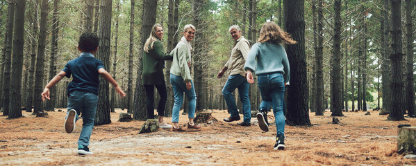 Forest, big family and adventure with children, parents and grandparents walking in nature for outdoor hiking, fun and trees on wellness vacation. Running kids, travel and happy man and women in wood