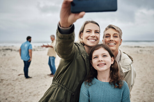 Phone, selfie and beach with a girl, mother and grandmother taking a family photograph on the sand by the sea while on vacation. Summer, technology and love with female relatives posing for a picture