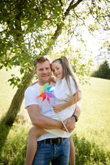 Father and daughter cuddle and have fun outside in nature with colorful pinwheel and are happy