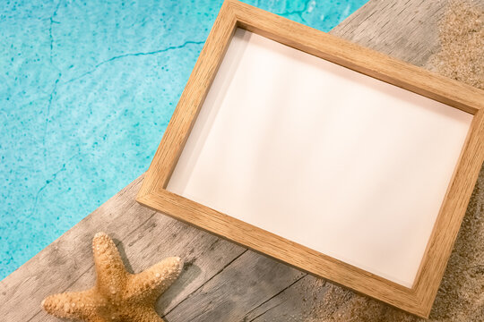 Cadre photos sans inscription vu du dessus sur un dallage en bois au dessus d'une piscine avec une étoile de mer. Ambiance vacances en été.	