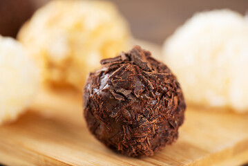 Traditional brazilian brigadeiro sweets with chocolate, coconut and cashew nuts in a plate, homemade, close-up.