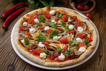 pizza with eggplant, cheese, tomatoes and chili peppers in a restaurant
