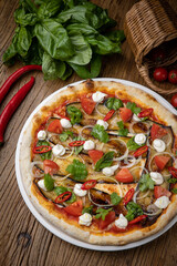 pizza with eggplant, cheese, tomatoes and chili peppers in a restaurant
