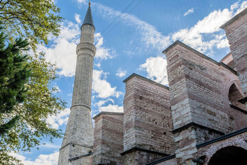 Fototapeta na wymiar Minaret towering above external wall of mosque