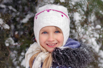 Winter day. A girl walks in a snowy park. Child on a walk in winter.