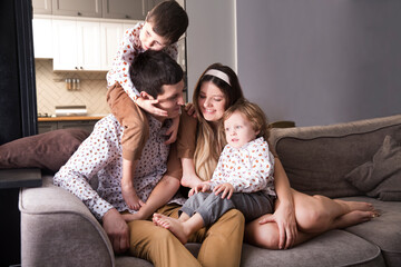 family has fun spending time together at home. mom, dad and two child son play, hugging and having fun together at home. Christmas time. 