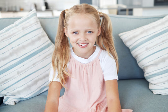 Children, Cute And Living Room With A Girl Sitting On A Sofa In Her Home Alone On The Weekend From Above. Portrait, Smile And Kids With A Happy Young Female Child Sitting In The Lounge Of Her House