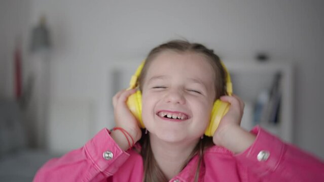 Cheerful little girl listening to music on headphones