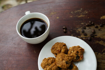 Black coffee cup with cookies on wooden floor, black coffee in the morning to drink with cookies.