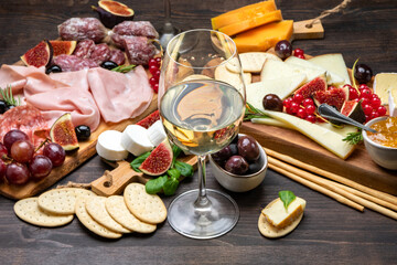 Antipasto platter cold meat plate with grissini bread sticks, Prosciutto crudo, Salami, olives and cheese.  Charcuterie board. Two glasses of white wine or prosecco