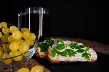 breakfast. black coffee. sandwiches with cottage cheese and parsley. green grapes