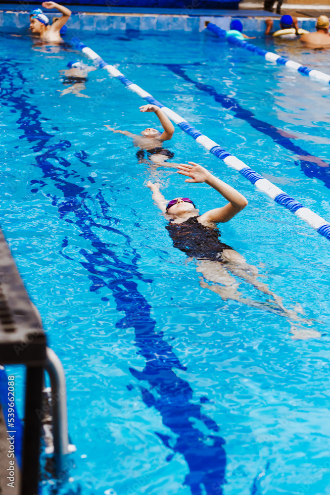 Wall mural latin young man swimmer athlete wearing cap and goggles in a swimming training holding on starting b