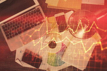 Financial market graph and top view computer on the desktop background. Multi exposure. Investment concept.