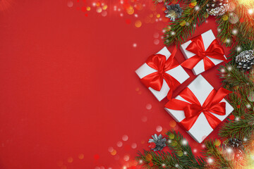  Spruce, fir branches, red berries, gift box on red background. Frame border. Christmas composition. Space for text.